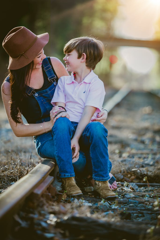Happy mother and son sitting together on a railway enjoying a sunny day.